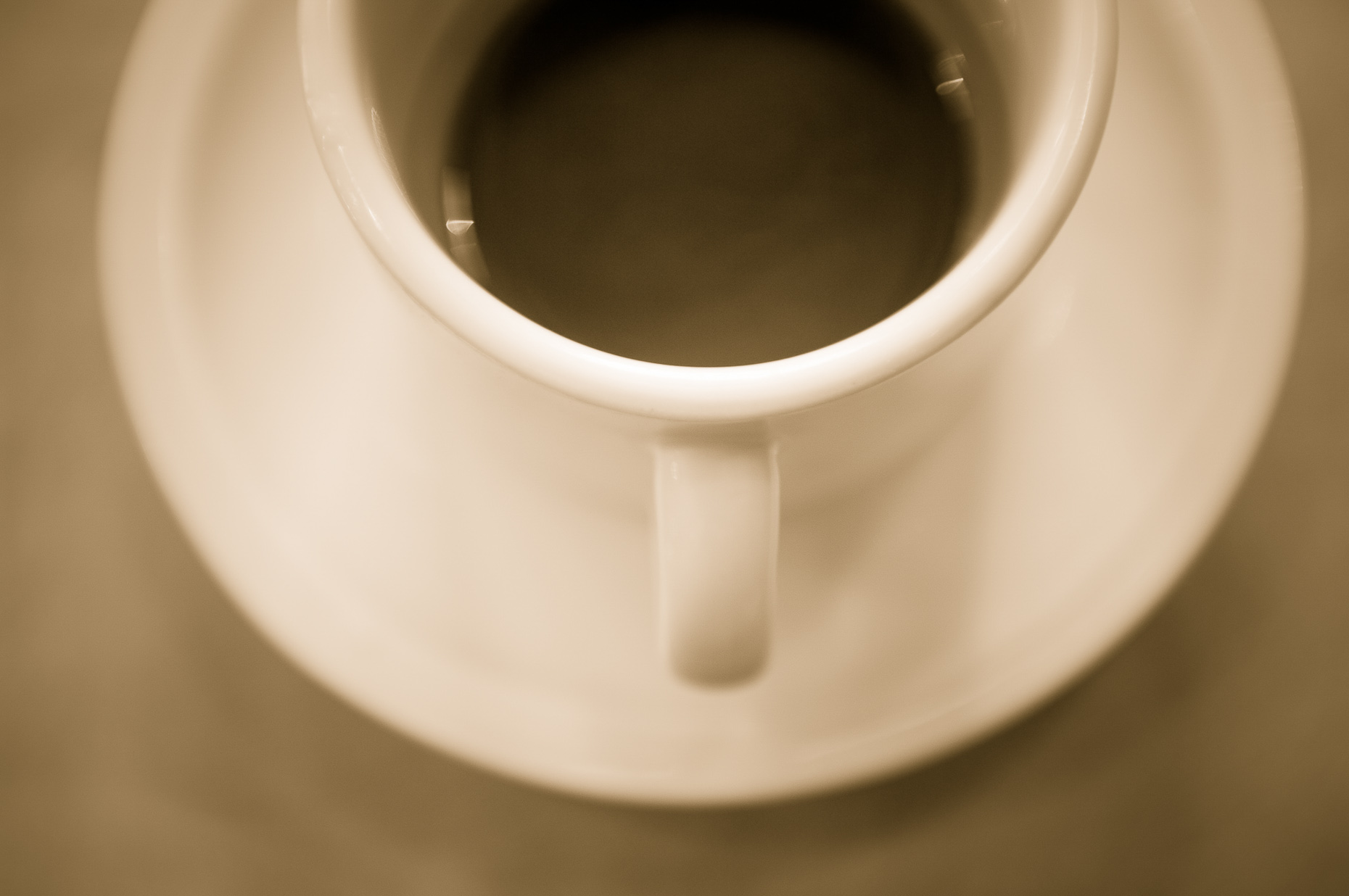 Sepia toned coffee cup and saucer shot from overhead.