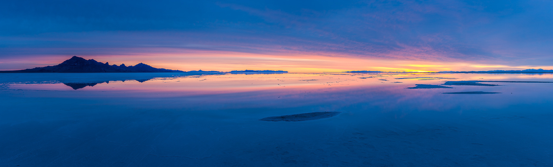 Panoramic image of dawn on Salt Lake, blue light and golden sun.  Bonneville Salt Flats, Utah.