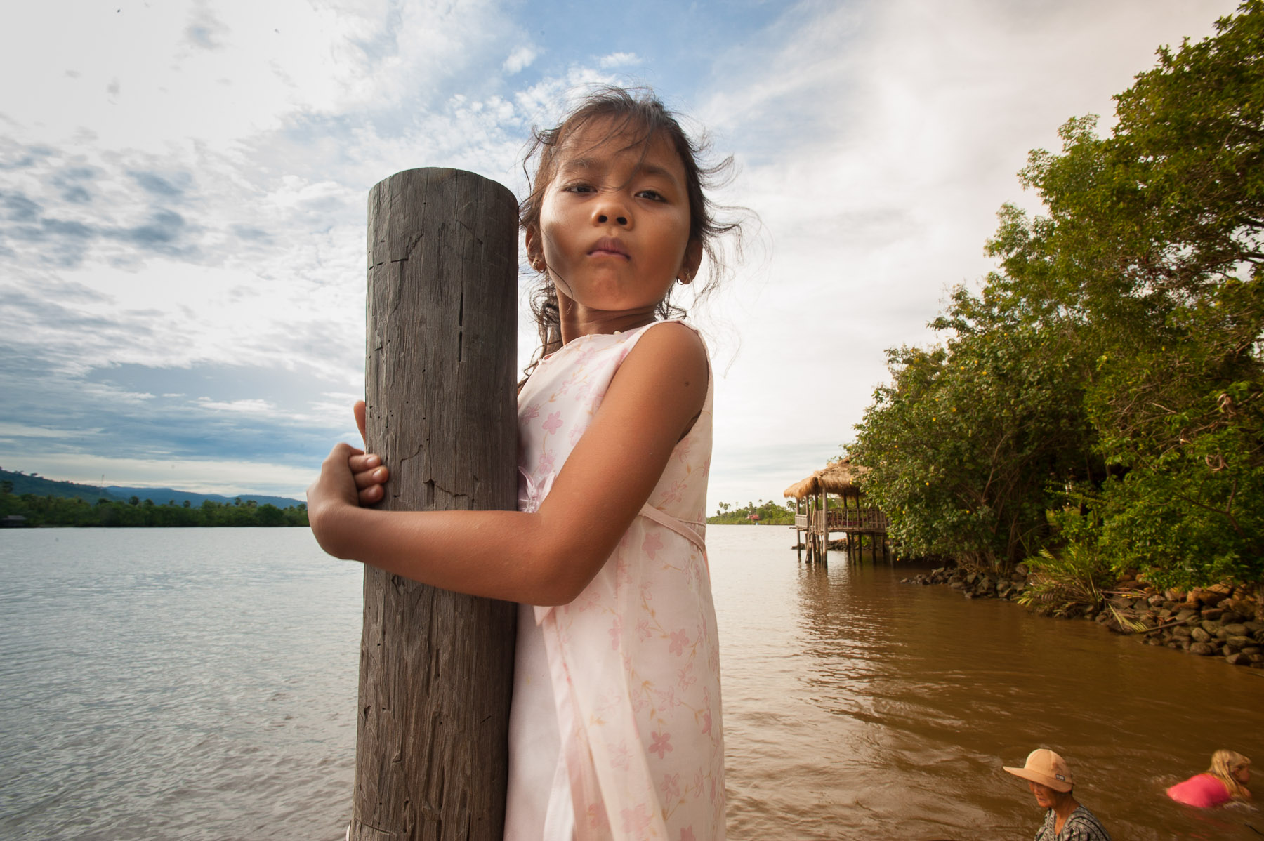 Young Cambodian girl on dock of river, Kampot, Cambodia.
