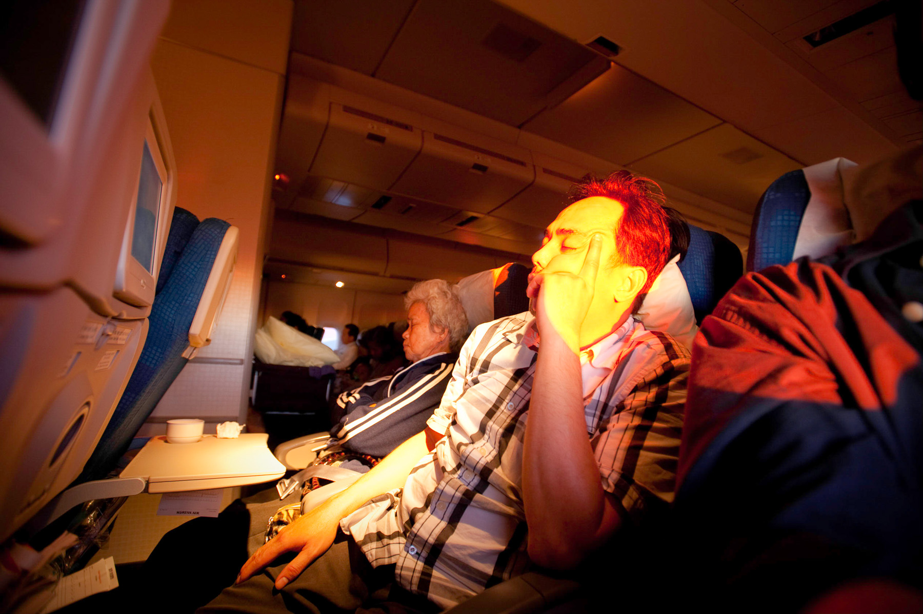 Cambodian man asleep on airplane ride to Seoul.