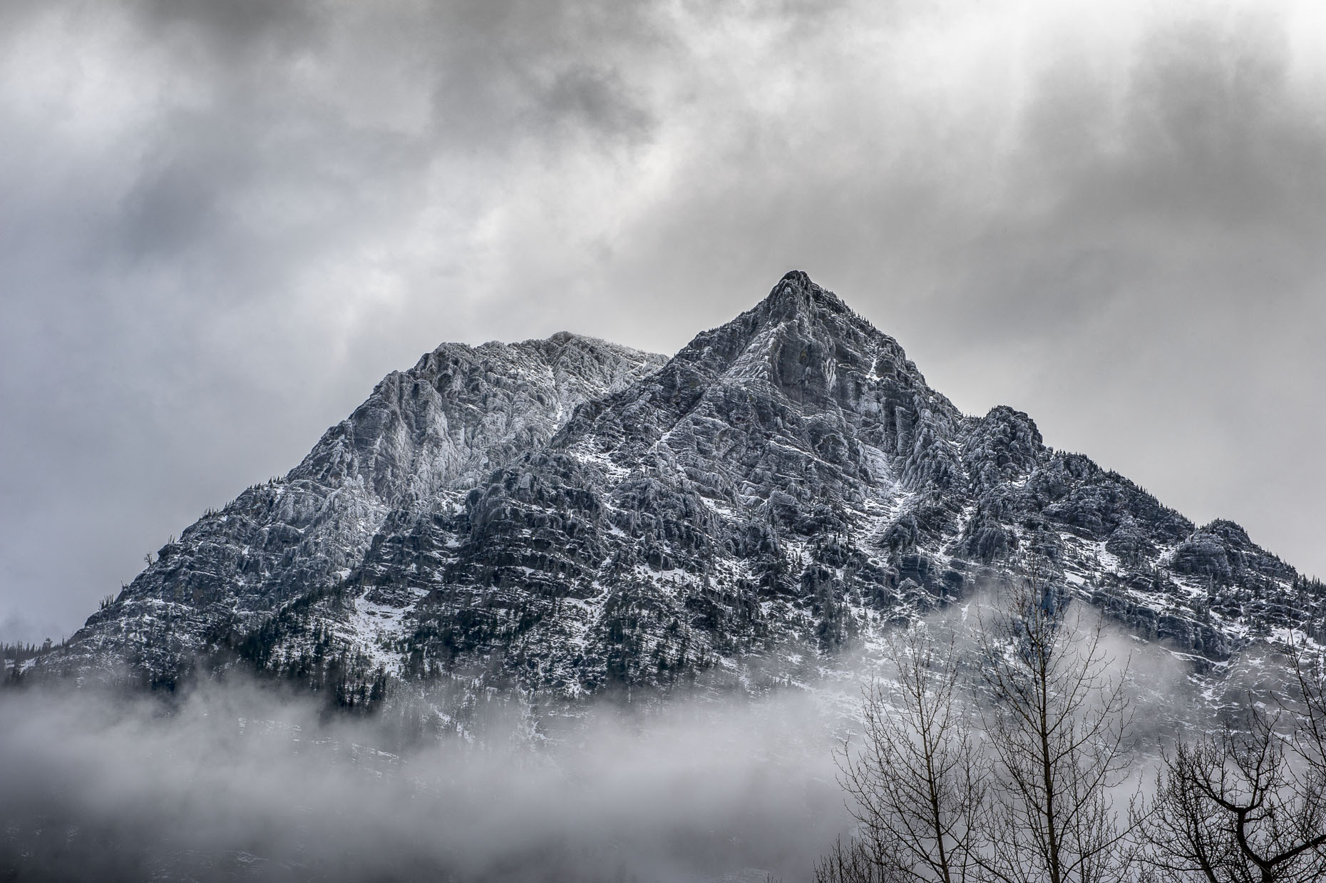 Image of granite peak in  snowy weather near mountain in Glacier National Park, WY. 