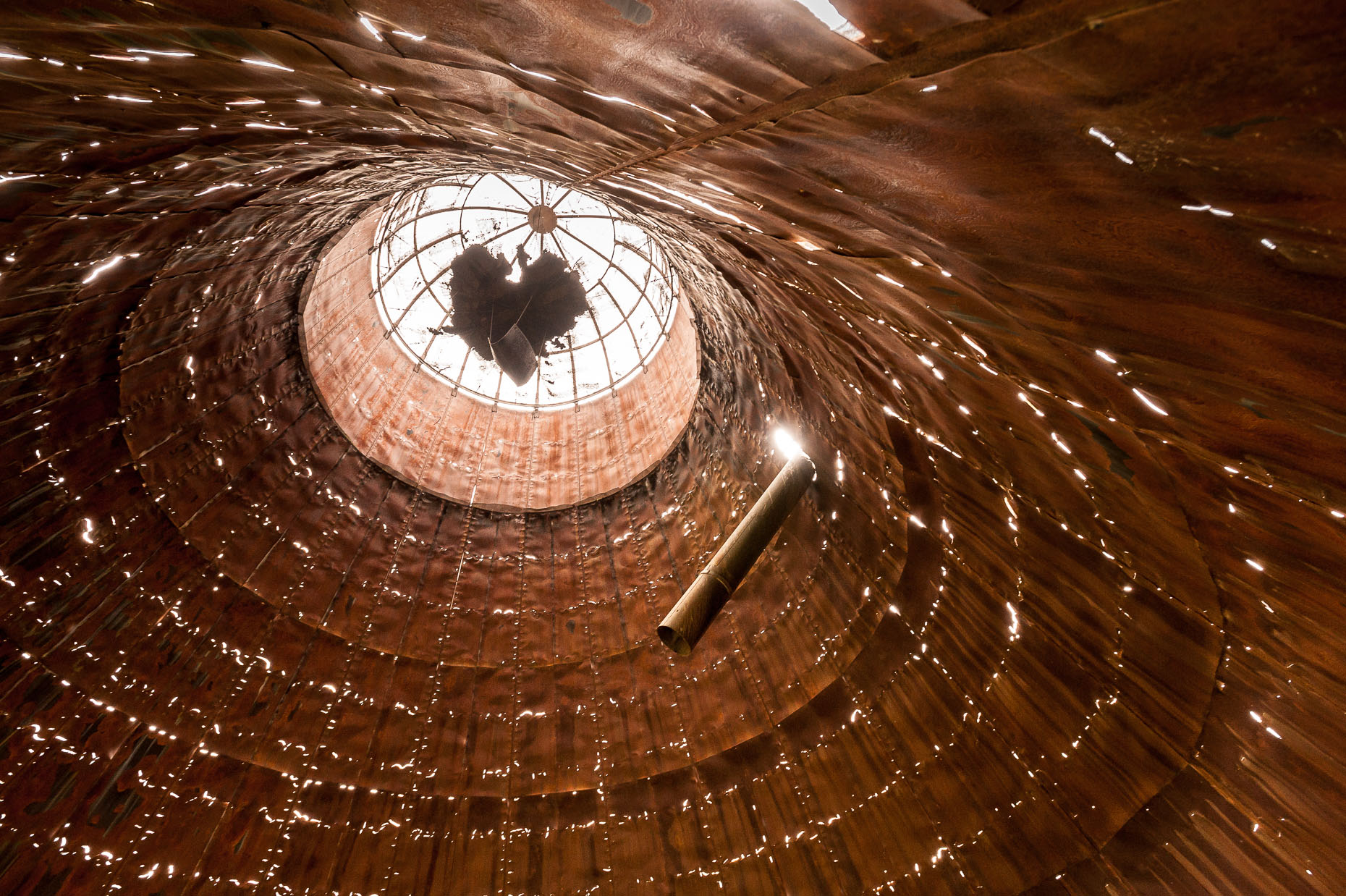 Photo of inside an old rusted sawdust containment building. 