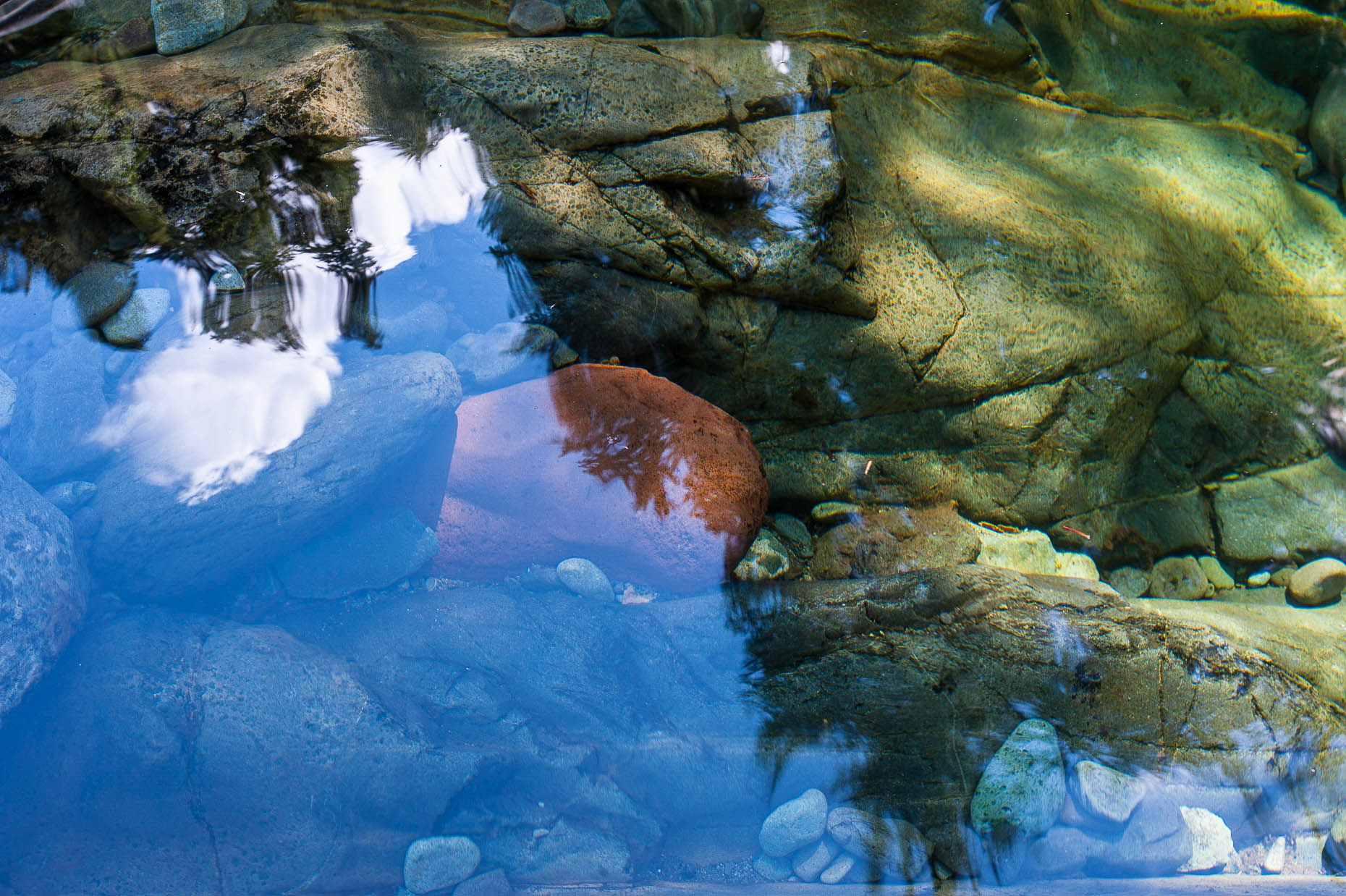 Photo of water reflection with river rocks under water.