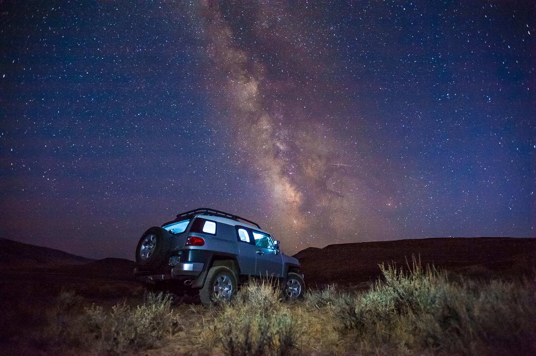 Image of Milky Way Galaxy and FJ Cruiser in desert. 