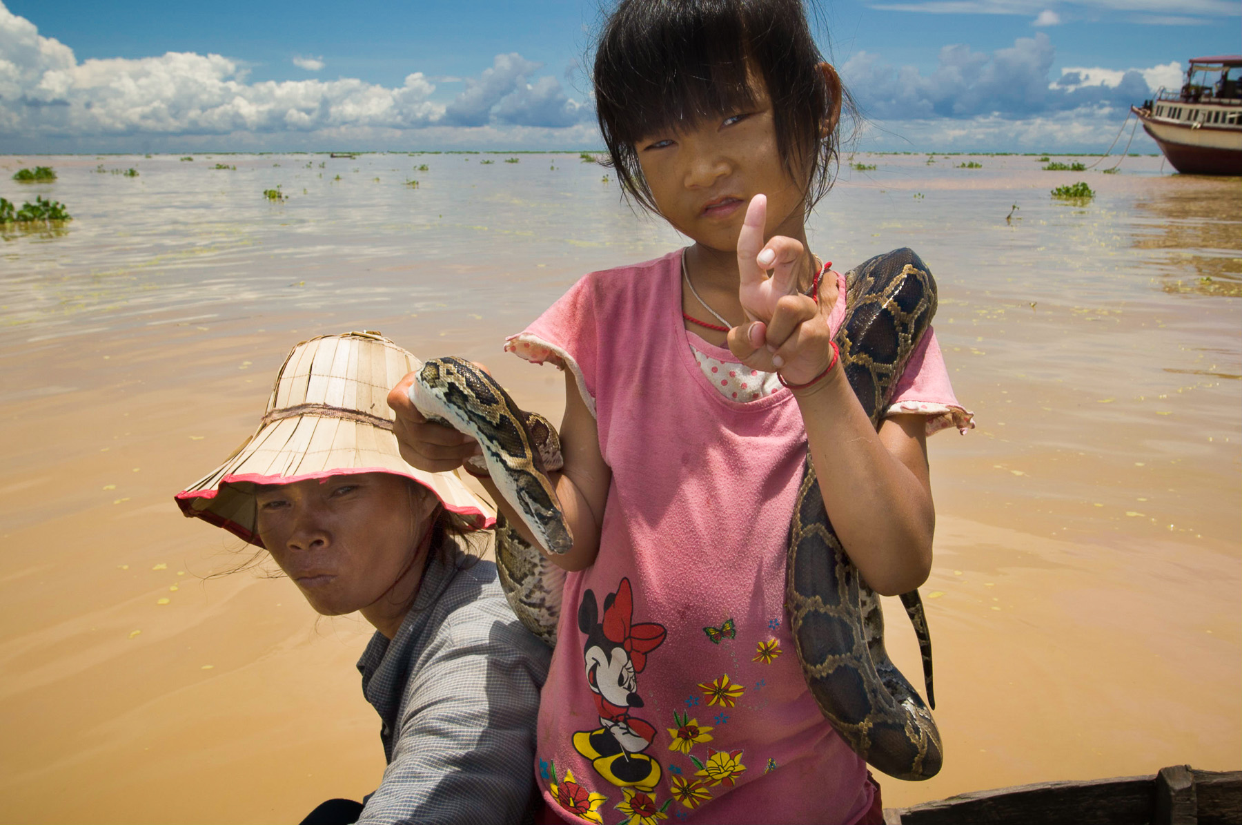 Begger girl with snake in floating village, Cambodia.