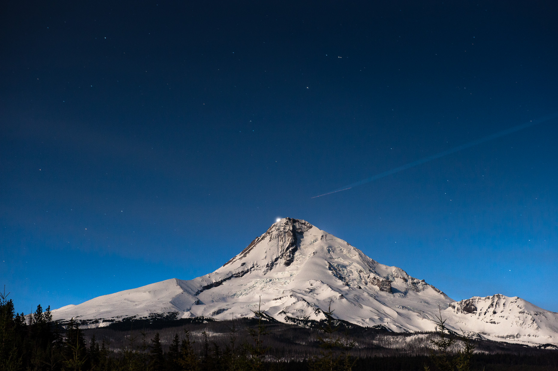 Nightime photo of Mt Hood with jet trails and backlit by Venus. 