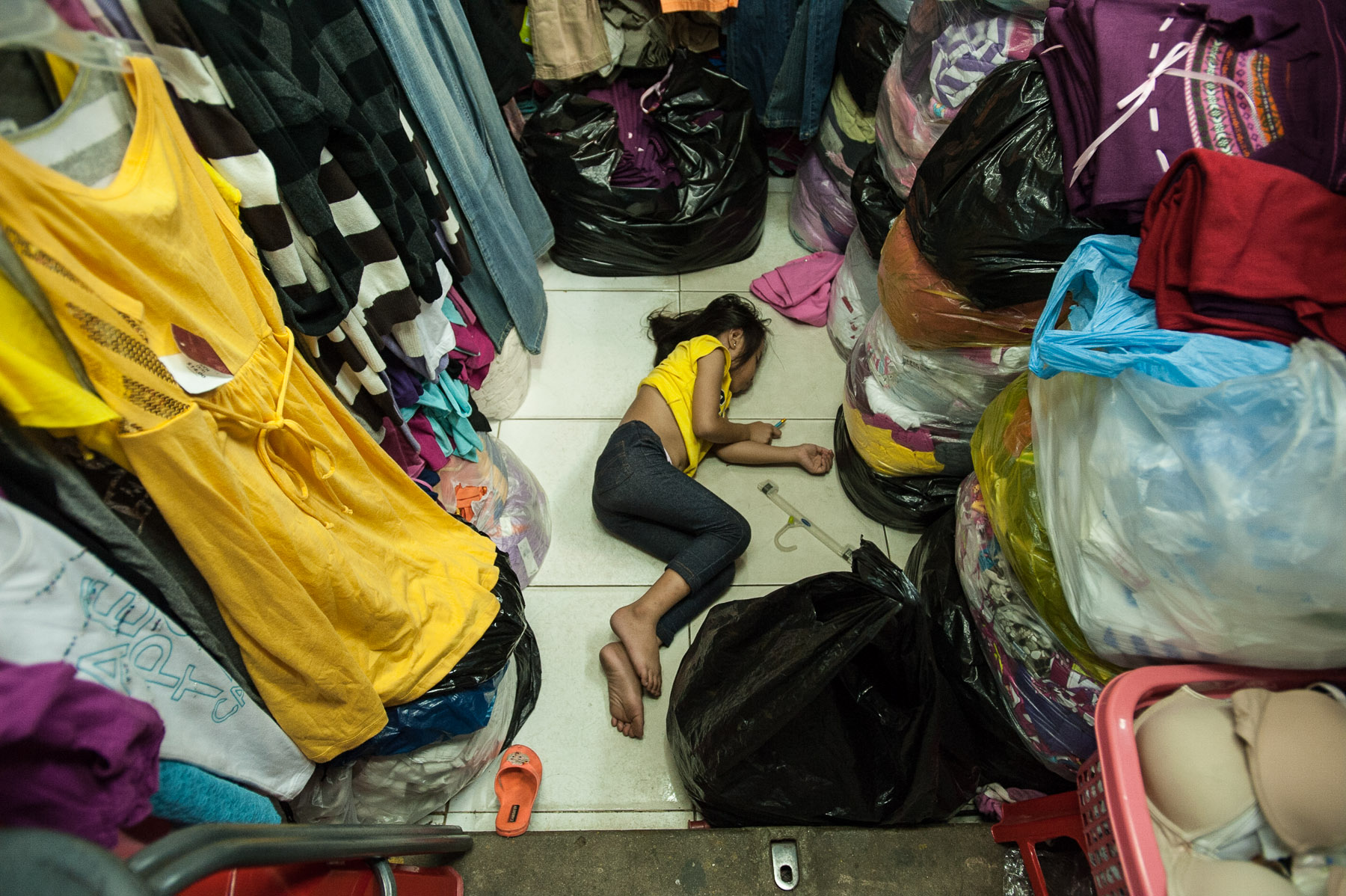 Girl asleep on floor of market stall, Russian market, Phnom Penh Cambodia.